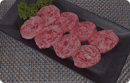 黒い皿の上に置かれる加工前の小判型ミニステーキ