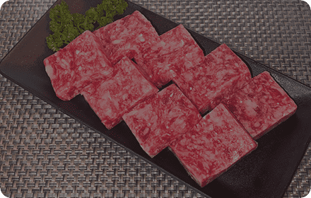 黒い皿の上に置かれる加工前のドミノ型ミニステーキ