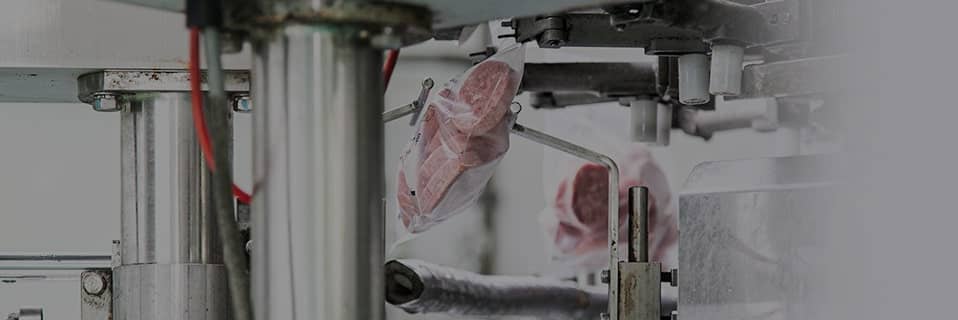 透明の袋に入った冷凍サイコロステーキをもつ従業員の手